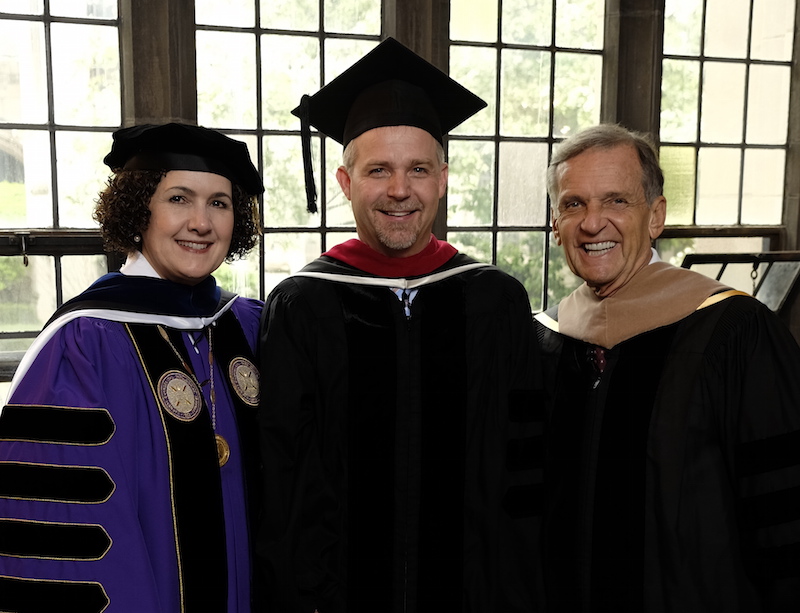 Garrett-Evangelical Distinguished Alum Franz S. Rigert poses in graduation robes with two men.