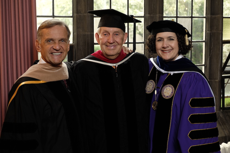 Garrett-Evangelical Distinguished Alum Samuel Phillips poses in graduation robes with two other people.