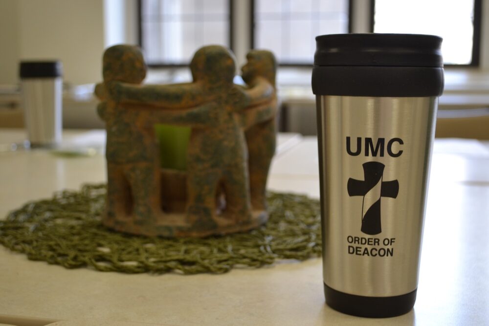 a travel mug that says order of deacon