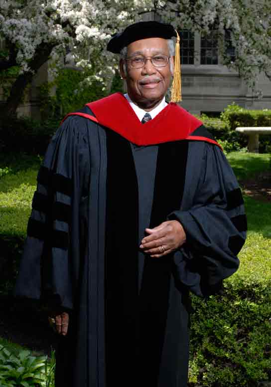 Distinguished Alum 2008 Charles Wesley Jordan stands in a garden on Garrett-Evangelical's campus. He is wearing graduation robes.
