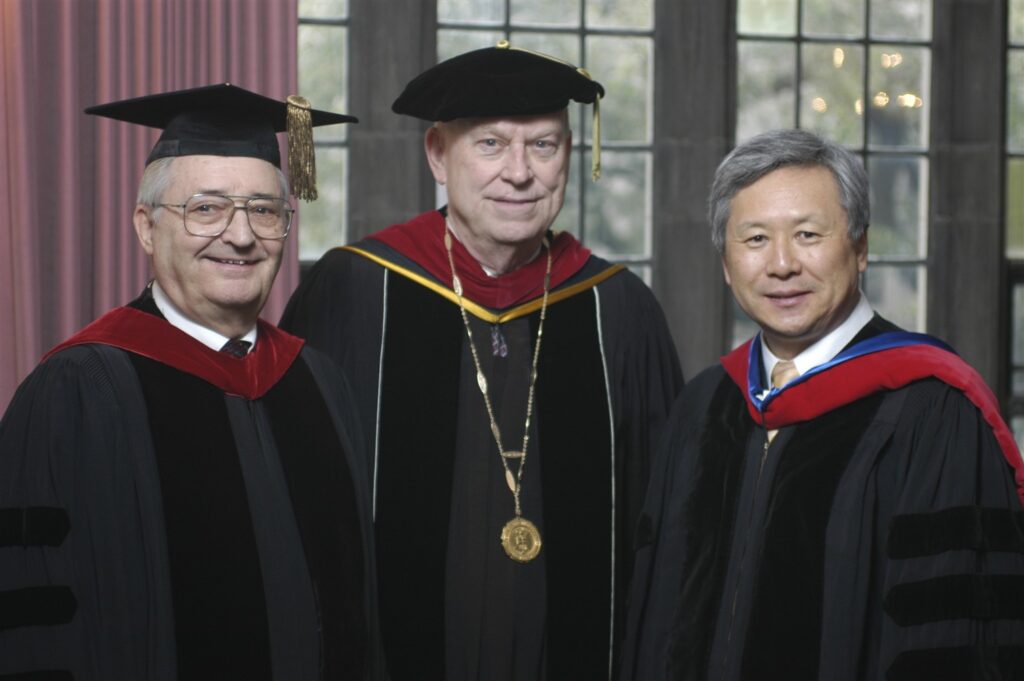 2009 Distinguished Alum award winners K. James Stein and Sang-Young Shim stand next to Garrett-Evangelical's president. All three people are wearing graduation robes.
