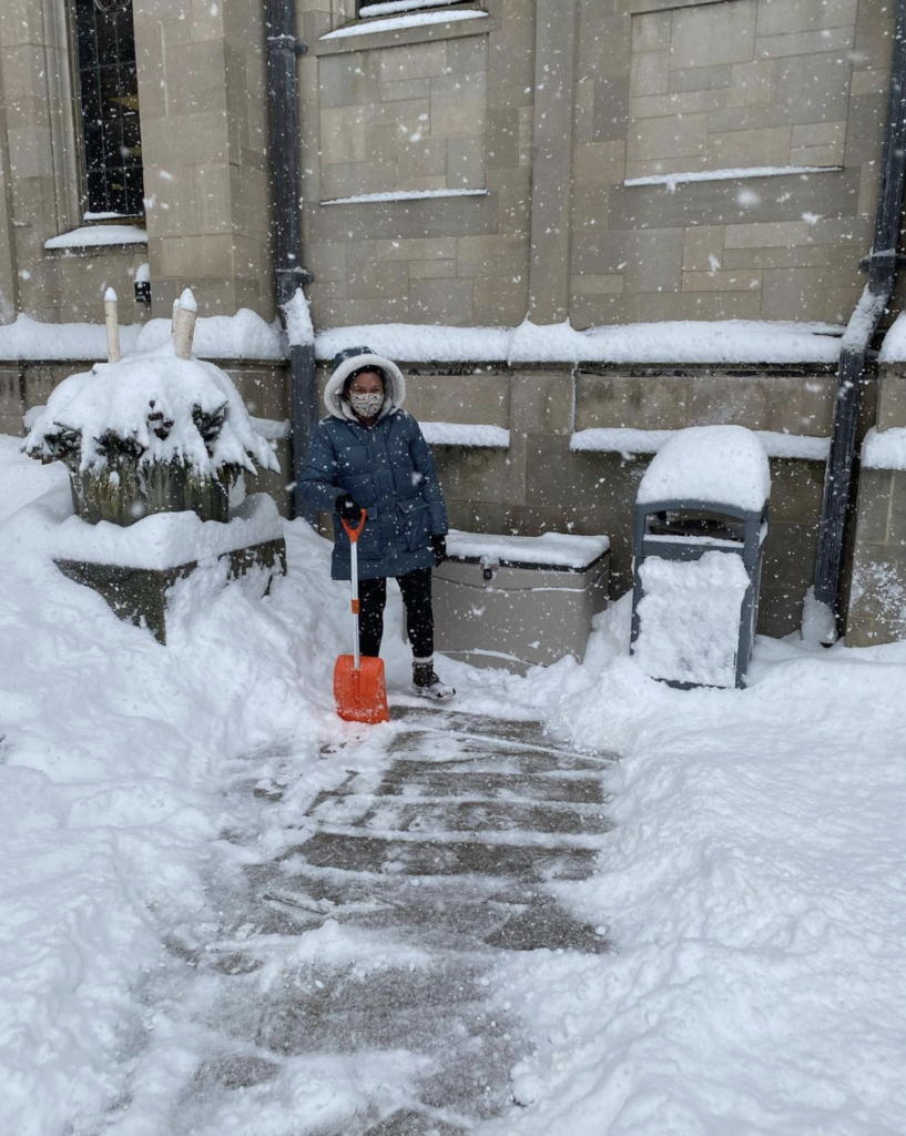 Library Worker shoveling snow from a curbside pickup bin