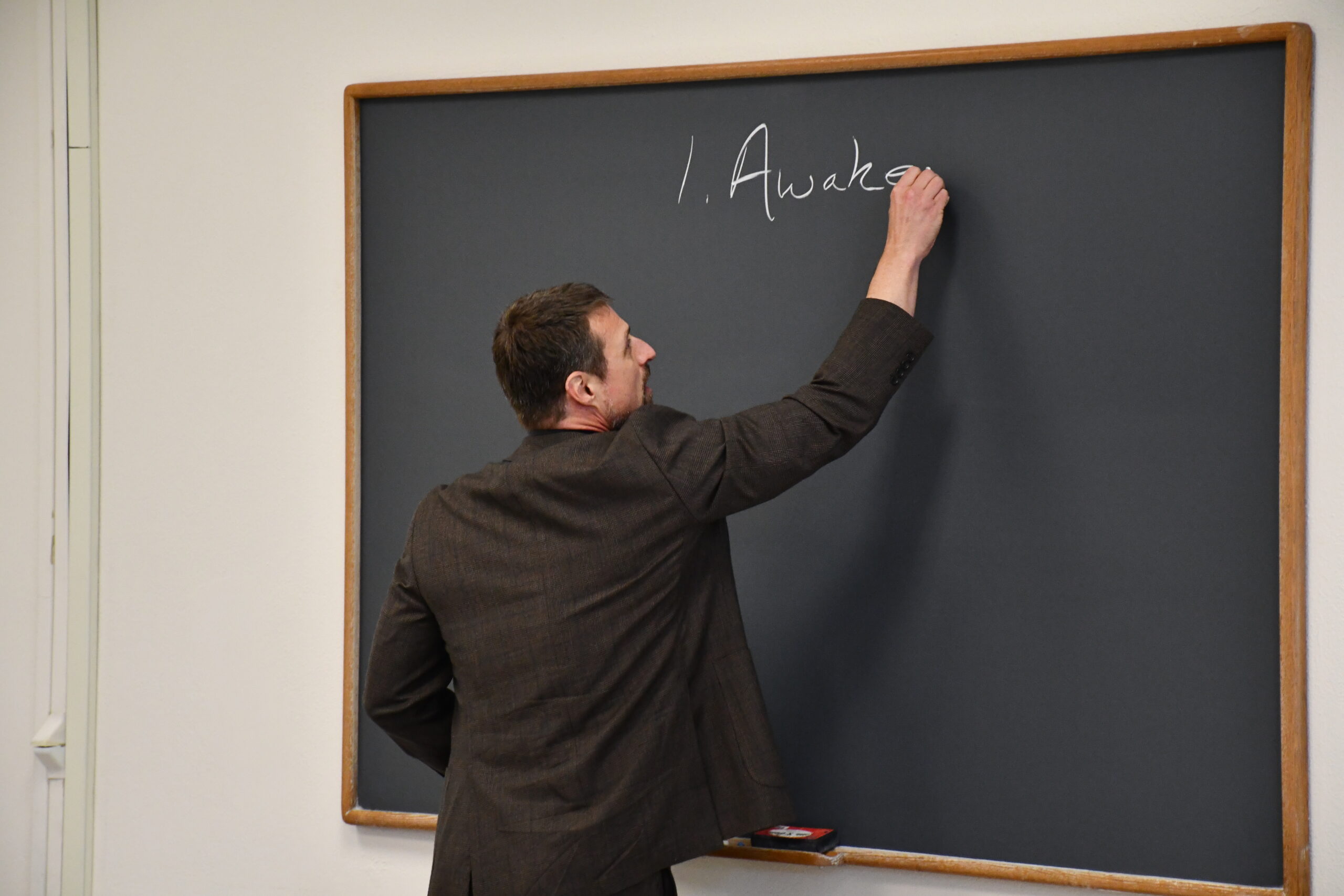 Professor standing at chalkboard in classroom